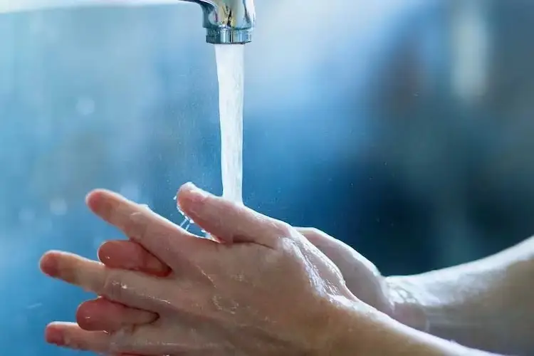 Hände werden unter Wasserhahn gewaschen.