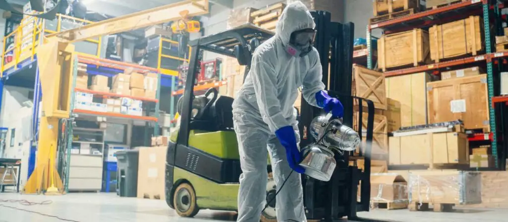 Person hält Sprühgerät in Industriehalle