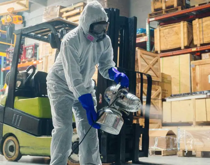 Person hält Sprühgerät in Industriehalle