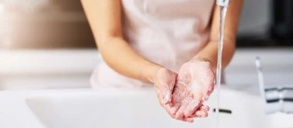 Eingeseifte Hände unter einem Wasserstrahl an einem Waschbecken