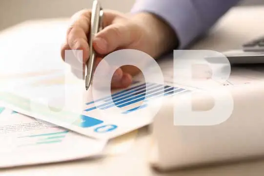 Hand h&auml;lt Kugelschreiber &uuml;ber Unterlagen mit Diagrammen darauf