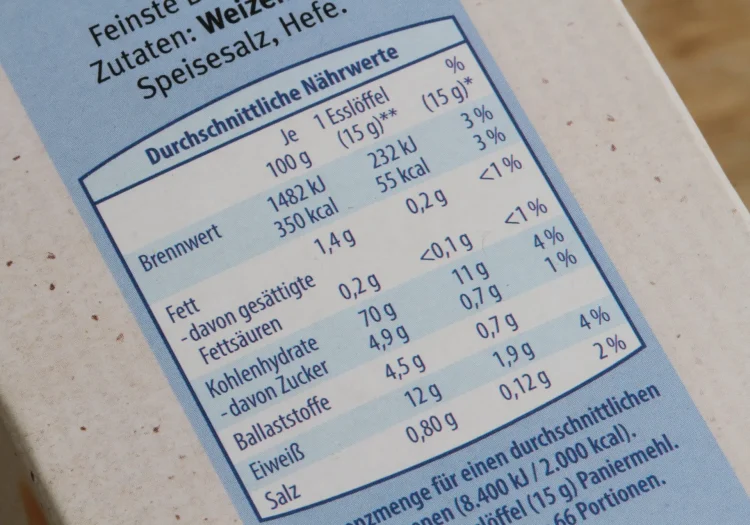 Eine Nahaufnahme einer deutschen Nährwerttabelle auf einer Lebensmittelverpackung mit Angaben zu Brennwert, Fett, Kohlenhydraten, Ballaststoffen, Eiweiß und Salz pro 100 g und pro Esslöffel (15 g).