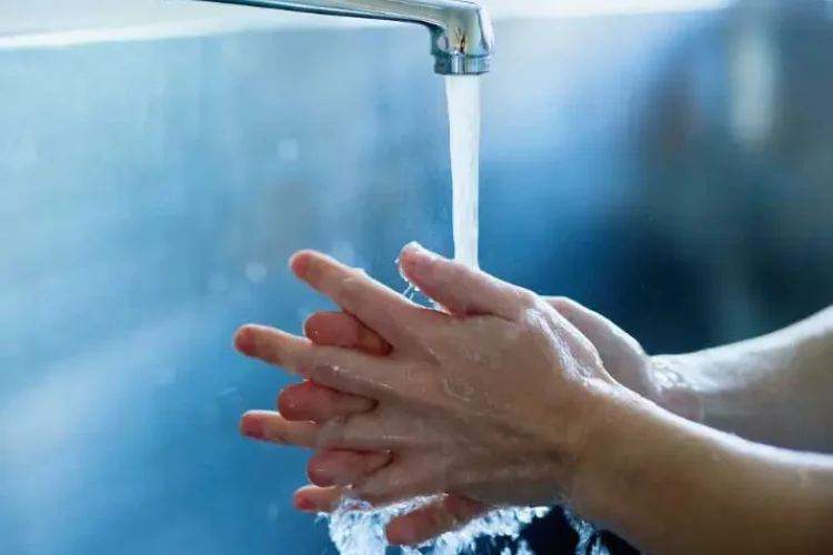 Hände werden unter Wasserhahn gewaschen